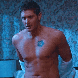 a shirtless man has a tattoo of a sun on his chest .