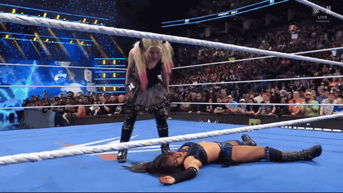 a female wrestler is laying on the floor in a wrestling ring