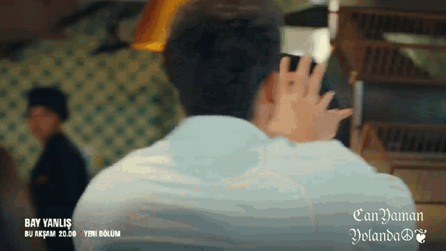 a man in a white shirt is talking on a cell phone with the words bay yanlis on the bottom left