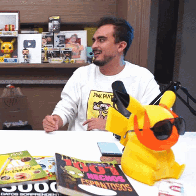 a man wearing a pink panther sweatshirt sits at a table