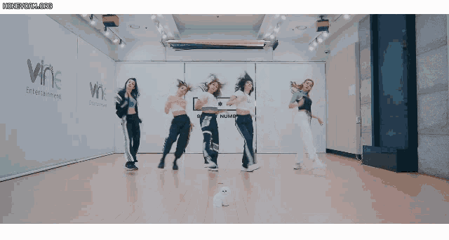 a group of women are dancing in front of a wall that says wne on it