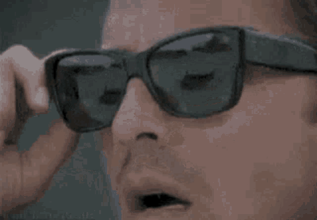 a man is wearing a pair of sunglasses and looking at them .