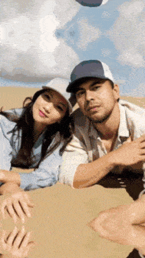 a man and a woman are posing for a picture while laying in the sand