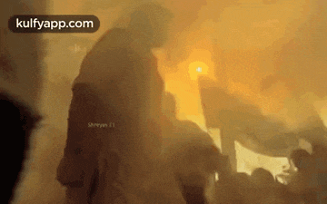 a man is standing in front of a crowd of people in a room with smoke coming out of it .