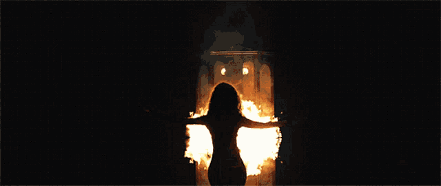 a woman is standing in front of a fire