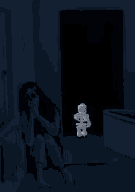 a woman is sitting on the floor in a dark room with a stuffed smurf .