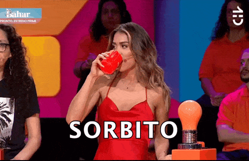 a woman in a red dress is drinking from a red cup with the word sorbito written on it
