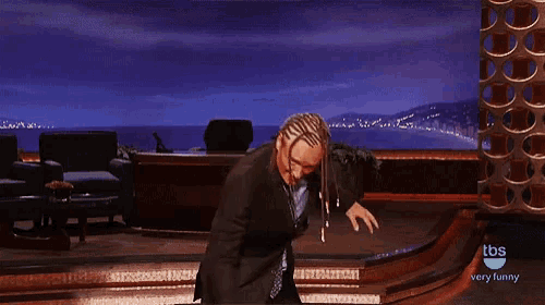 a man in a suit is dancing on a stage in front of a tbs sign