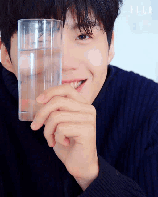 a close up of a person holding a glass of water in front of their face