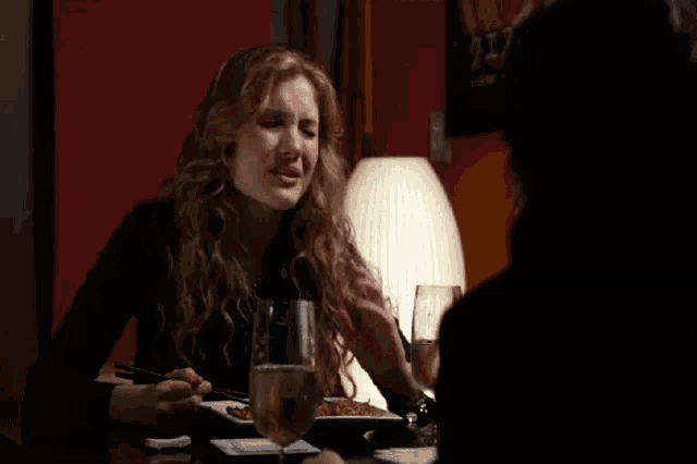 a woman sitting at a table with a glass of wine and a plate of food
