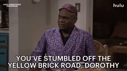 a man is sitting at a table with a plate of food and says you 've stumbled off the yellow brick road