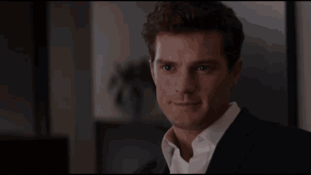 a man in a suit and white shirt is smiling and looking at the camera