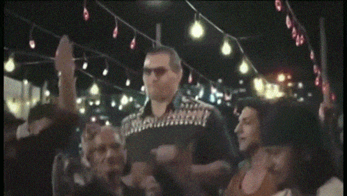 a man wearing sunglasses is surrounded by a crowd of people