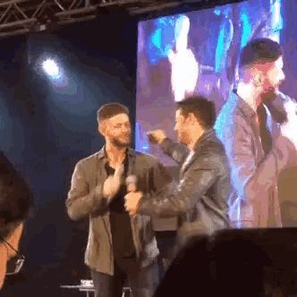 two men are standing next to each other on a stage with microphones .