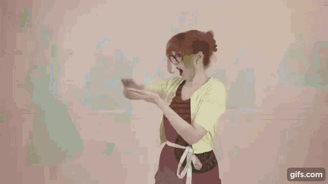 a woman with glasses is eating a sandwich while standing in front of a crowd of people .