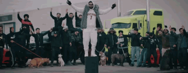 a man in a raptors jersey stands in front of a crowd
