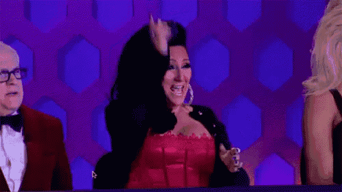 a woman in a red corset is sitting in front of a purple background .