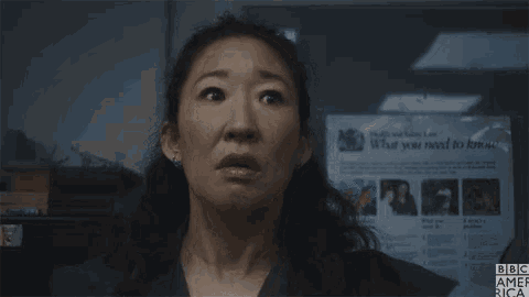 a close up of a woman making a surprised face in front of a poster .