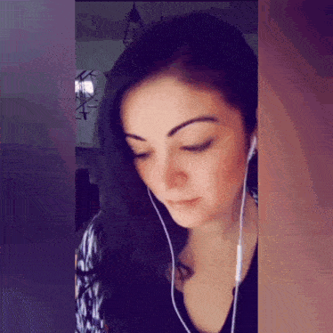 a woman wearing ear buds looks down at something