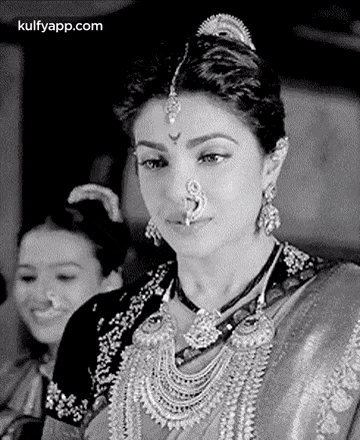 a black and white photo of a woman wearing a nose ring and a necklace .