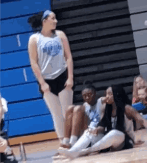 a group of young women are sitting on the floor of a gym .