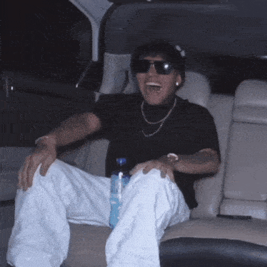 a man sitting in the back seat of a car with a bottle of water in his lap