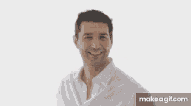 a man in a white shirt is smiling and looking away from the camera