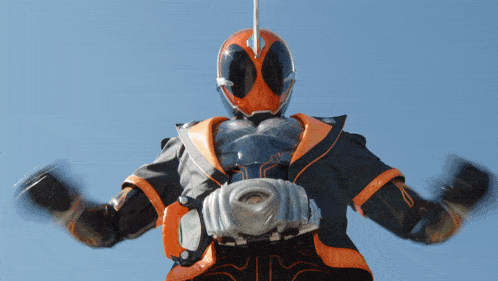 a man in an orange and black superhero costume is standing with his arms outstretched