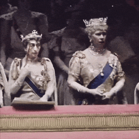 a woman in a crown is standing next to another woman in a dress