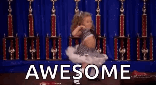 a little girl is dancing in front of a row of trophies and the words `` awesome '' are above her .