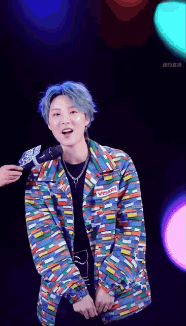 a man wearing a colorful jacket with a vision label on it