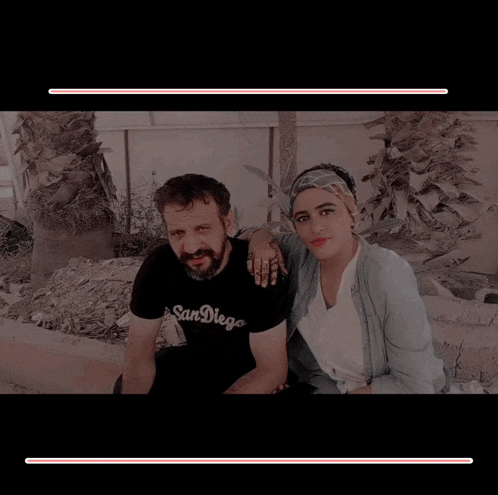 a man wearing a san diego shirt sits next to a woman wearing a headband