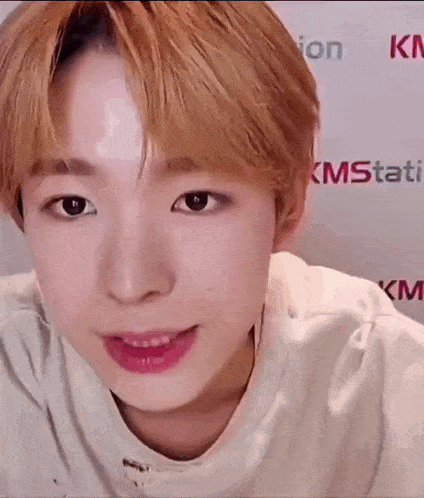 a close up of a young man 's face with a white shirt on and pink lips .