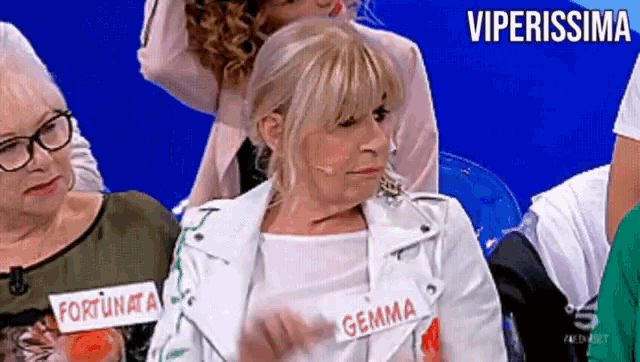 a woman wearing a white jacket has a name tag that says gemma