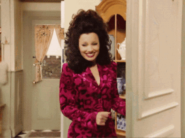 a woman in a pink dress is standing in a doorway smiling