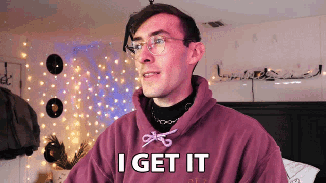 a man with glasses and a purple hoodie says i get it