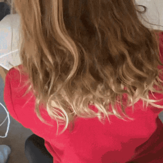 a woman in a red shirt is sitting down with her back to the camera
