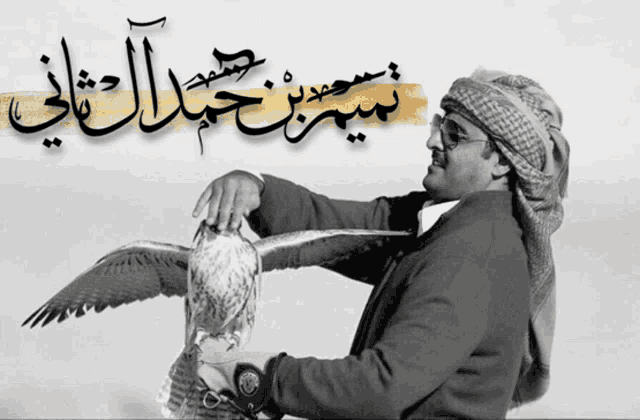 a man holding a bird with arabic writing on the bottom right