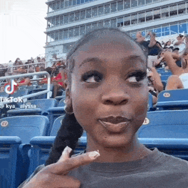 a woman is making a funny face while sitting in the stands at a sports game .
