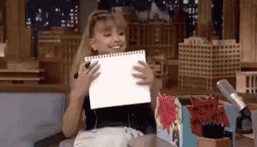 a young girl is holding a piece of paper in her hands and smiling .