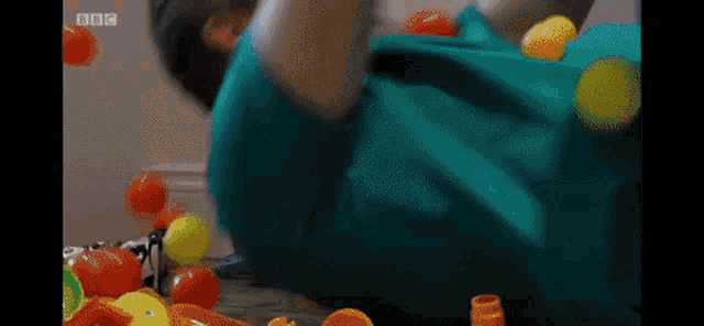 a blurry picture of a child playing with balls with bbc written on the bottom