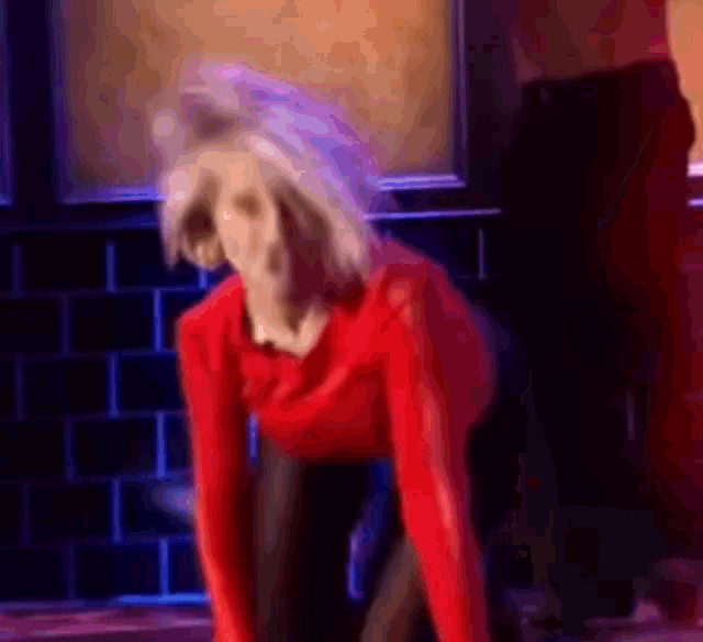 a woman in a red sweater is kneeling down on a stage .