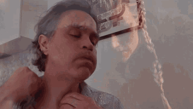 a man with his eyes closed has a reflection of himself in a mirror behind him