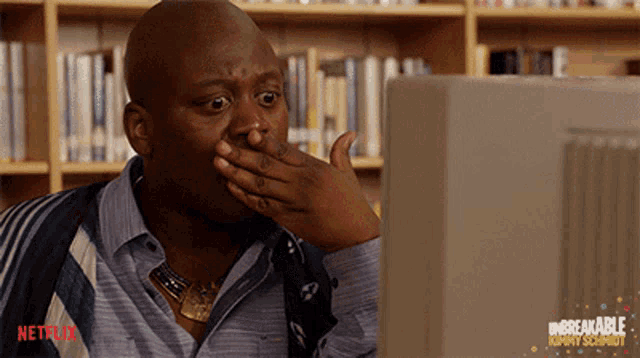 a man covering his mouth with his hand while looking at a computer screen that says netflix on it