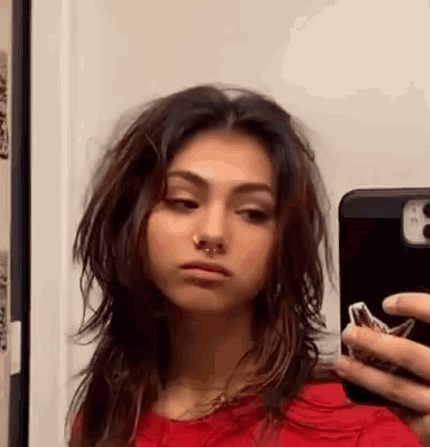 a woman is taking a selfie in a mirror with a nose ring .