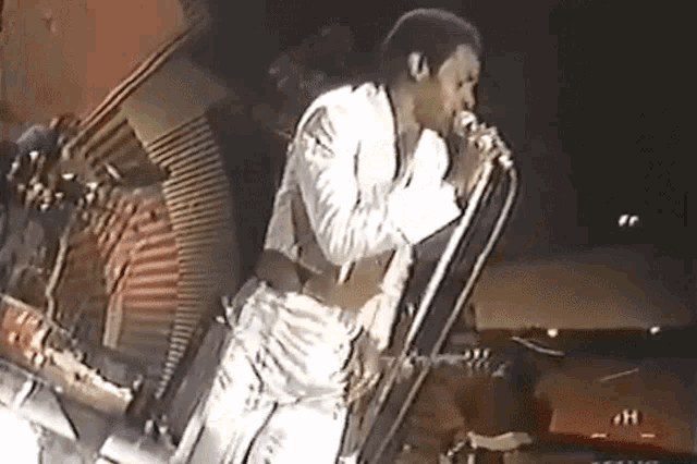 a man singing into a microphone with the letter h on the bottom