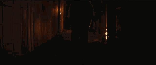 a person is walking down a dark alleyway with a fire in the background