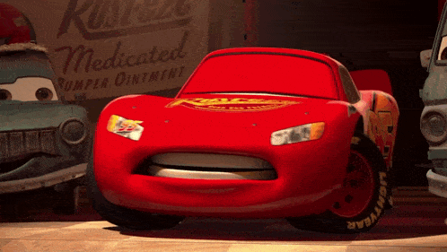a red lightning mcqueen car is standing in front of a rusteze medicated bumper ointment sign