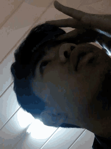 a man holds his hand to his forehead while looking at the camera
