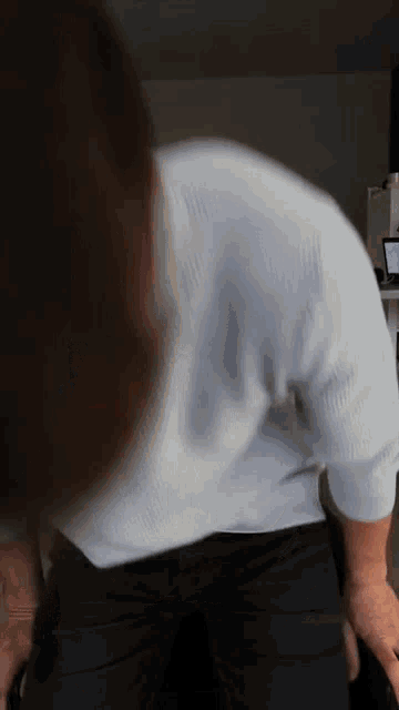 a man in a white shirt and black pants stands in front of a laptop